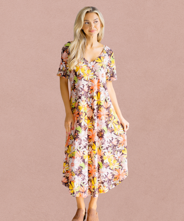 Woman wearing a floral dress against a pink background | Three Mad Hatters Mercantile