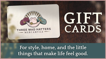 Gift card with 'Three Mad Hatters Mercantile' logo on a wooden background | Three Mad Hatters Mercantile | Jackson, MS