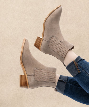 Gray suede ankle boots with wooden soles worn with blue jeans on a beige background | Three Mad Hatters Mercantile